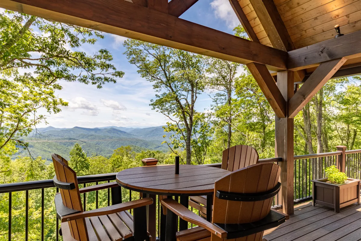 A tranquil wooden deck with a table and chairs overlooking a majestic mountain view. The deck is perfectly positioned for relaxing, dining, or socializing while immersed in nature.