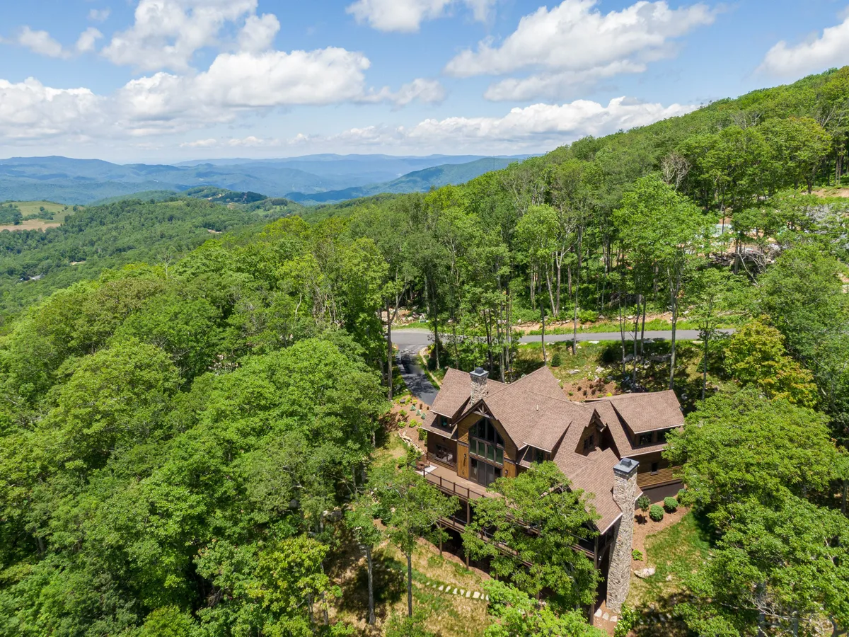 The exterior of the house is showcased with surrounding trees and a stunning mountain range in the background. The setting exudes tranquility and invites exploration of the natural environment.
